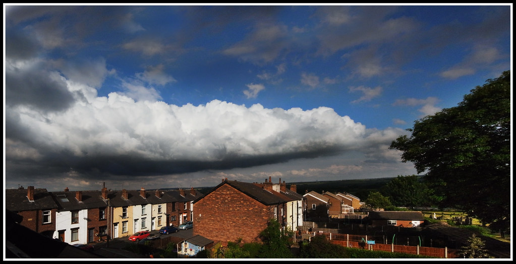 Storm clouds building over a row of rooftops (representative photo)